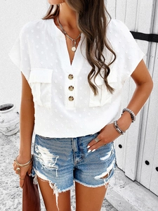 Detail of white V-neck short sleeve top with textured Swiss dots and flap pockets