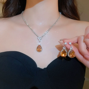 Detail view of amber teardrop jewelry set featuring crystal necklace and earrings on a model
