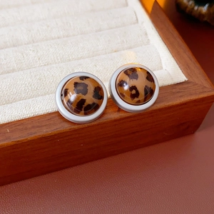 Gros plan de boucles d'oreilles rondes léopard avec bordure blanche sur bois