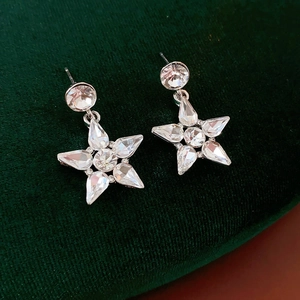Close-up of star shaped silver drop earrings with sparkling zircon stones on velvet