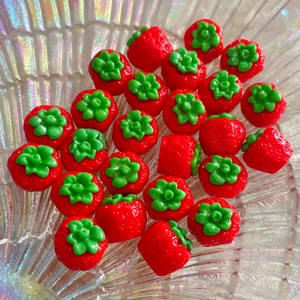 Dettaglio di mini ciondoli a fragola in resina per accessori per capelli fai-da-te