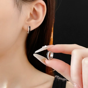 Detail of geometric zircon hoop earrings with black enamel inlay on stainless steel