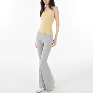 Detail of yellow halter top and grey flared yoga pants on model in a studio setting