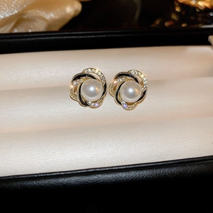 Detail of vintage gold plated earring with white pearl, black enamel and rhinestones