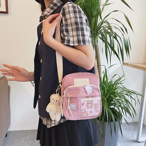 Sac bandoulière en toile rose avec un pendentif ours peluche et des autocollants