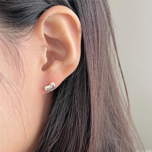Macro view of minimalist 925 sterling silver bean stud earrings on a model ear
