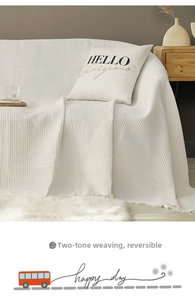Detail of cream waffle textured sofa cover with long fringe and double-sided woven pattern