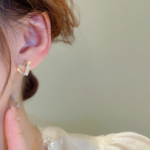 Close-up of heart-shaped gold studs with sparkling zircon stones worn by a model