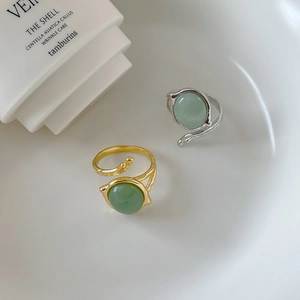 Detailed view of silver and gold organic branch rings with round green jade stones