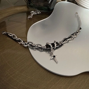 Detail of silver chain bracelet with black rectangular charm and cross pendant