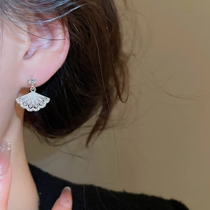 Detailed close-up of fan-shaped silver earrings with sparkling cubic zirconia on model