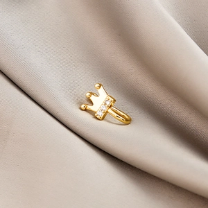 Macro shot of gold-plated crown nose clip with micro-inset zircons on satin fabric