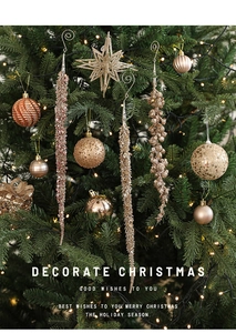 Close-up of gold and champagne sequined Christmas ornaments hanging on a green tree branch