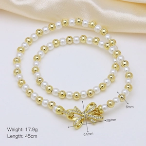 Detailed view of natural pearl necklace with golden beads and a bow-shaped pendant