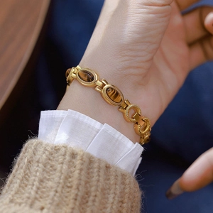 Macro detail of vintage gold chain watch featuring oval brown tiger eye stones on a wrist
