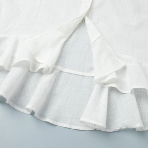 Vue détaillée du haut en lin blanc avec ourlet à volants et patte de boutonnage