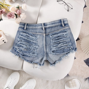 Close-up of distressed denim shorts with frayed edges and large ripped details on back