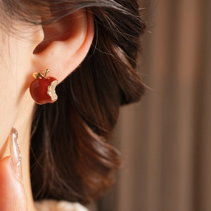 Close-up of red apple flower earring with diamonds on a model's ear in warm light