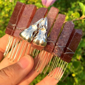 Macro shot of dark red crystal hair comb with silver crow skull accents and metal wire