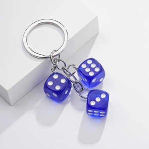 Detail of silver metal keychain with three blue transparent dice charms on white background