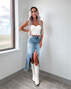 Détail de jupe en jean taille haute avec ourlet à franges vieilli et fente latérale haute