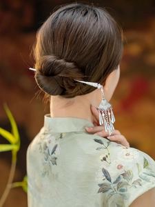 Detail of vintage Miao silver hair pin with dangling tassels on a classic updo