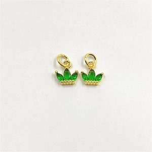 Macro detail of gold crown charms with green zircon inlay for DIY jewelry design