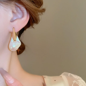 Primo piano di una modella che indossa orecchini di perle barocche con accenti in metallo dorato
