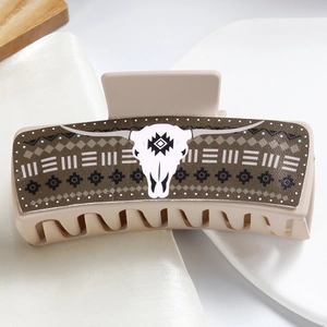 Detail of a beige rectangular hair claw clip featuring a brown bohemian bull skull pattern