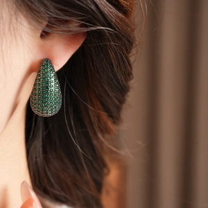 Gros plan d'un mannequin portant des boucles d'oreilles gouttes vertes en zircon