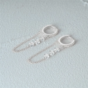 Macro shot of 925 silver hoop earrings with diamond chains and sparkling tassels