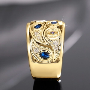 Vue macro d'une bague large dorée ajourée avec pierres précieuses bleues et jaunes