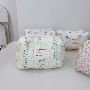 Détail de pochettes à maquillage matelassées fleuries avec texte élégant français