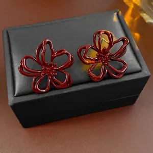 Orecchini a fiore traforato bordeaux con finitura smaltata su una scatola di gioielli