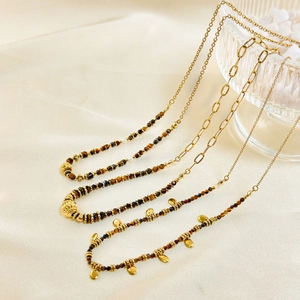Macro view of natural tiger eye stone beads and gold alloy chains on beige silk fabric