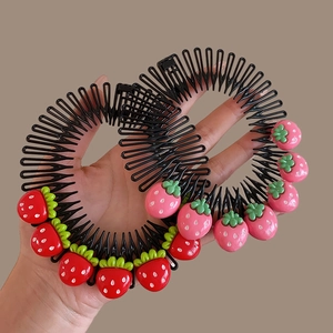Detail of children's strawberry hair side combs with red and pink fruit charms held in hand