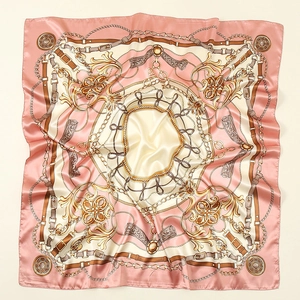 Close-up of pink satin square scarf with golden chain and vintage medal prints
