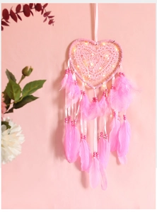Detailed close-up of pink heart-shaped dreamcatcher with warm LED lights and feathers