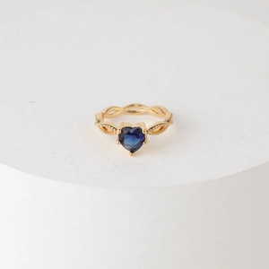 Elegant gold-tone heart-shaped blue gemstone ring with intricate twisted rope band
