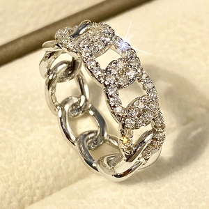 Macro shot of silver chain link ring with micro-paved zircons on beige velvet