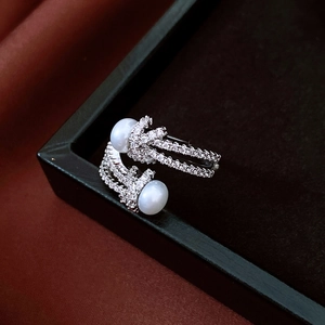 Detail of elegant silver ring with dual white pearls and zircon knot design