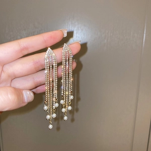 Détail de boucles d'oreilles à pampilles avec strass brillants et perles blanches élégantes