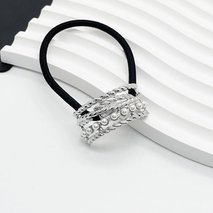 Detail of black elastic hair tie with silver twisted metal and white pearl embellishment