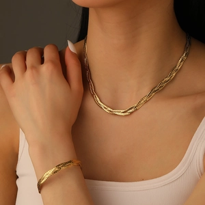 Three-strand braided gold necklace and bracelet jewelry set worn by a fashion model