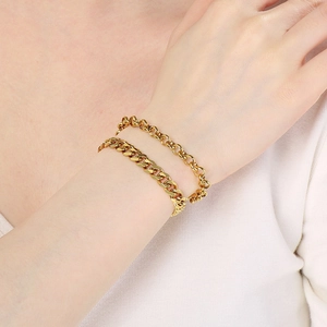 Detailed view of layered gold-plated Cuban and ring-link bracelets on female wrist