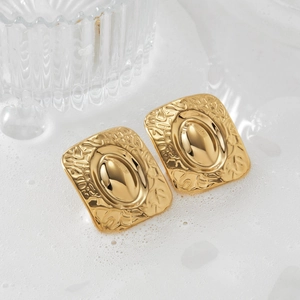 Golden square hammered metal earrings with oval relief center in a minimalist aesthetic