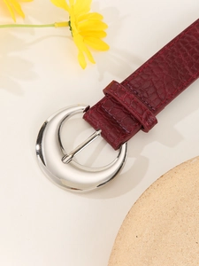 Detailed close-up of wine red crocodile pattern leather belt with silver crescent buckle