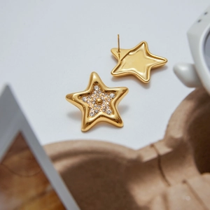 Vue macro détaillée de boucles d'oreilles étoiles dorées avec strass clairs et fini poli