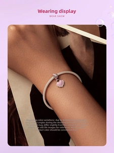 Détail du bracelet en maille d'argent s925 avec pendentif cœur rose et nœud au poignet