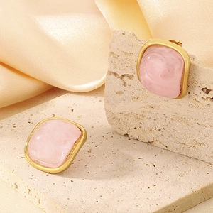 Détail de boucles d'oreilles carrées en résine rose et acier inoxydable doré poli